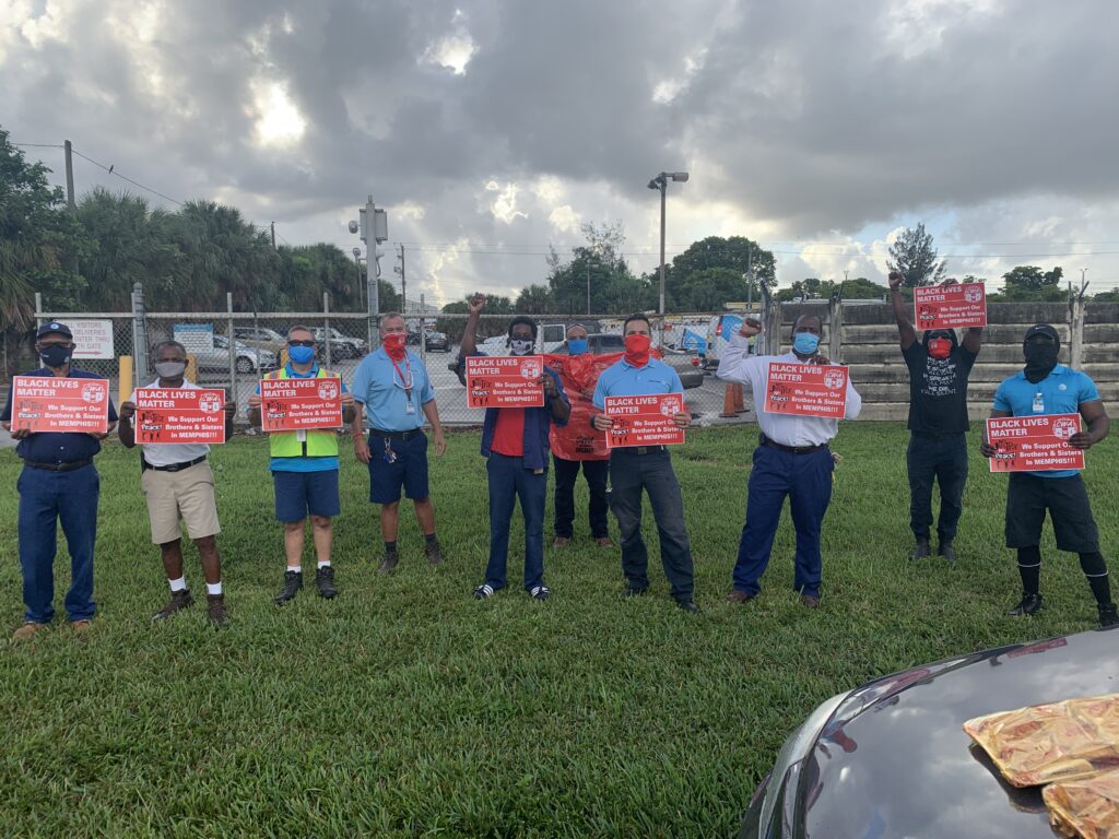 A group of people holding signs in the grass.