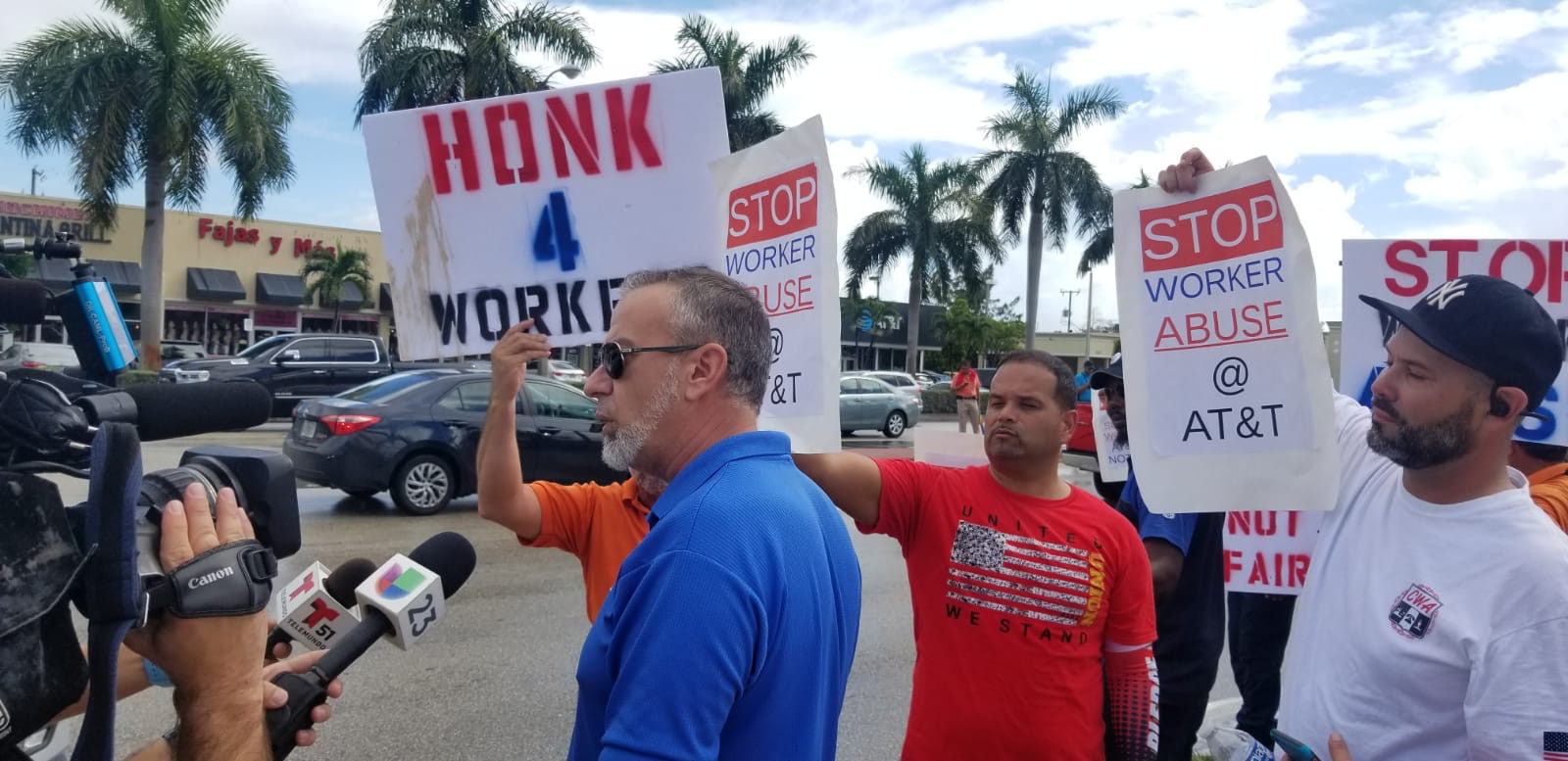 Protesters hold signs against AT&T worker abuse.