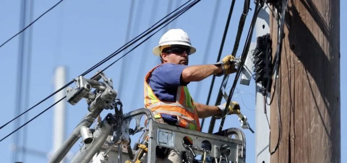 Worker repairing power lines on utility pole.